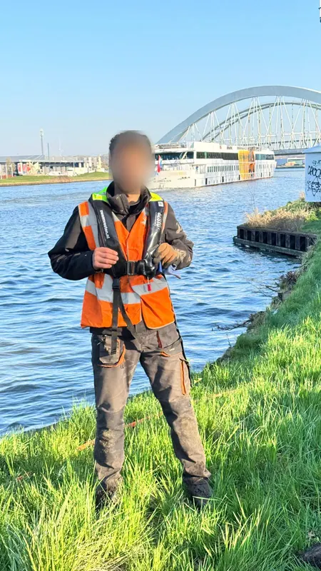 Medewerker met reddingsvest langs het water